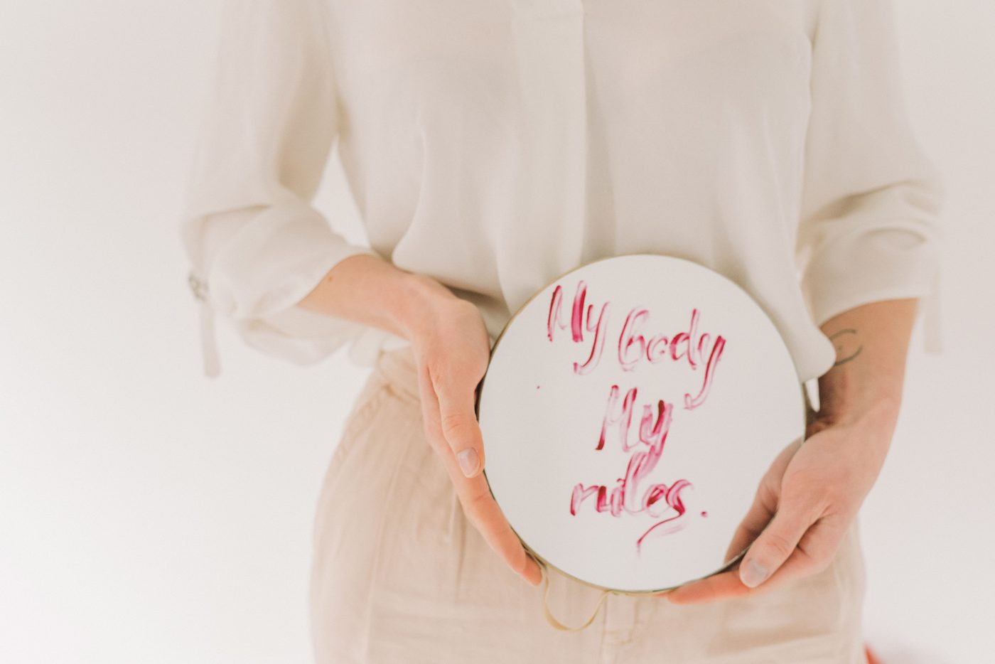 A woman holding a cardboard sign that reads my body, my rules