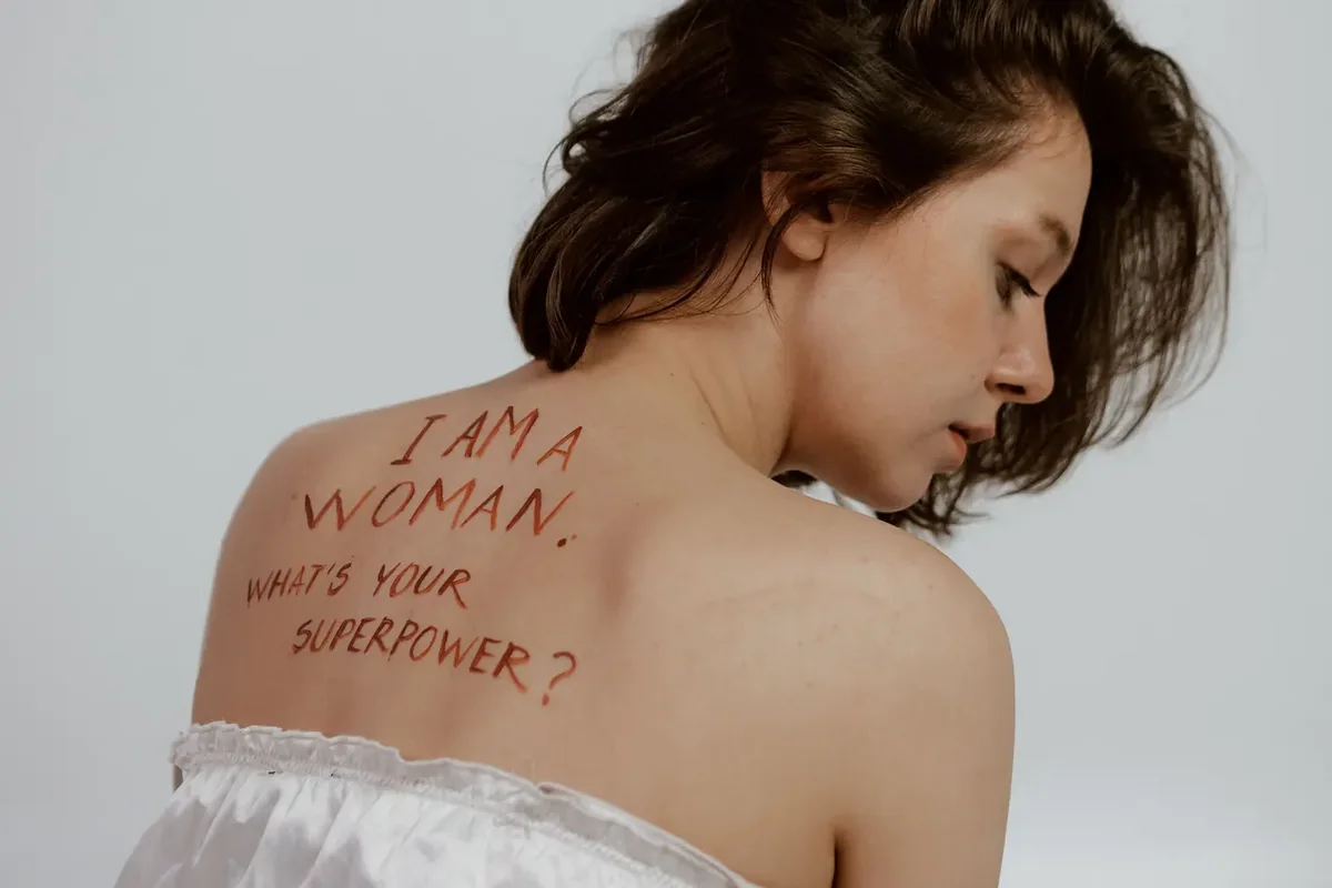 A poster on a pale wall that reads Woman, what is your superpower, with my cycle written underneath in pen. Image credit: Polina / Pexels